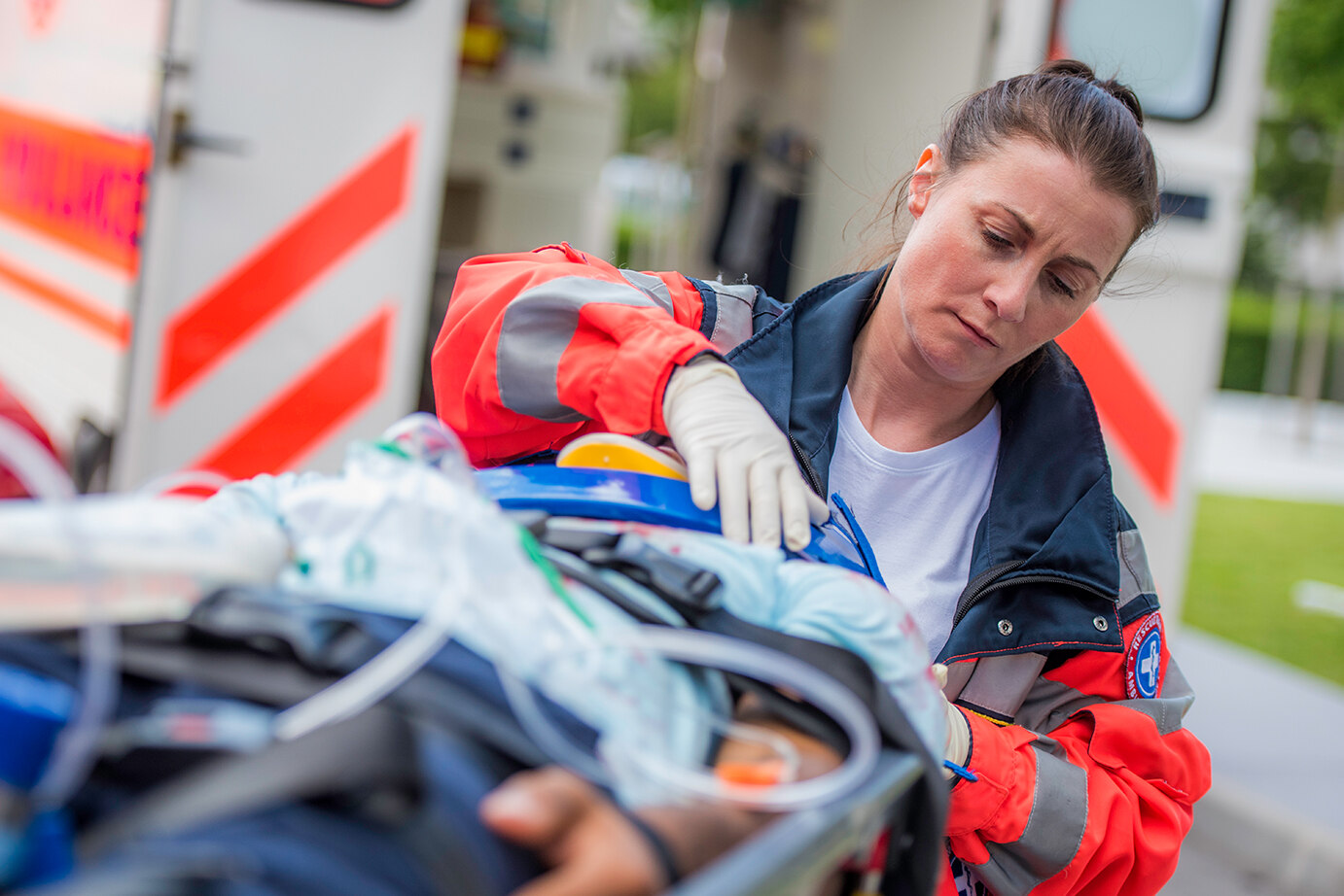 Notfallsanitäterin steht neben einem Patienten, der auf einer Trage liegt